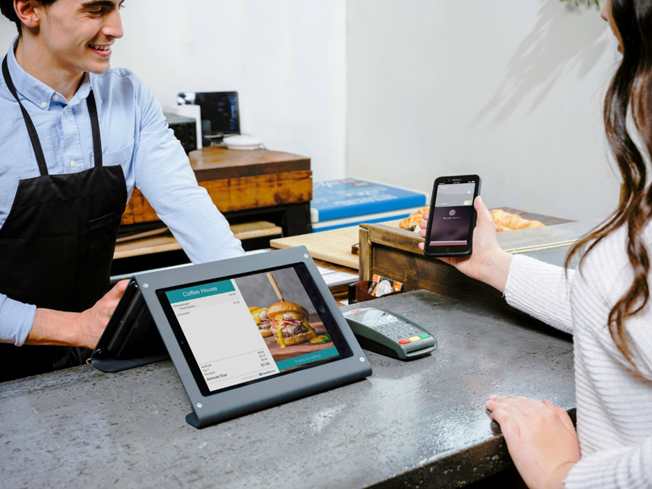 Woman paying with a POS system at a restaurant counter