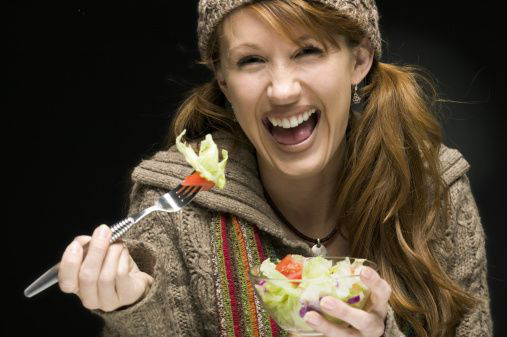woman laughing alone with salad